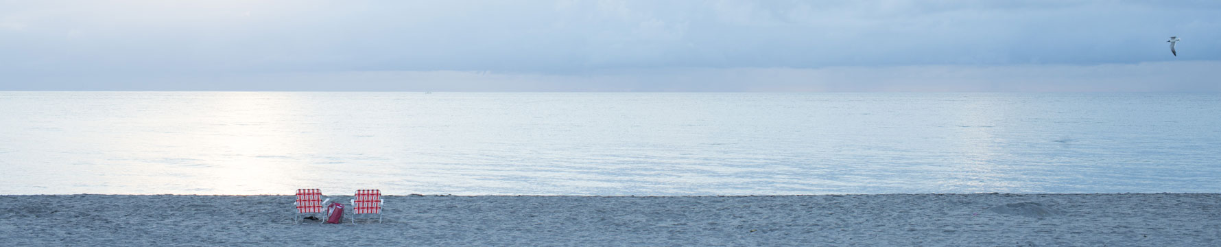 Two empty chairs on a beach looking over the ocean