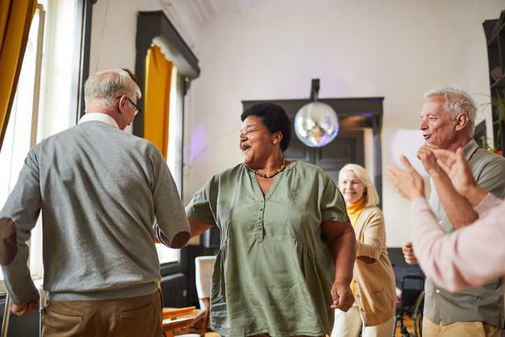 Diverse group of smiling senior people dancing while enjoying activities in retirement home