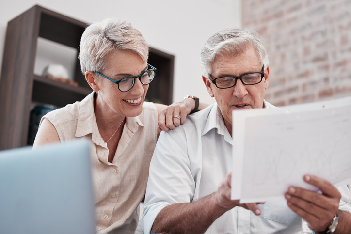 older adult husband and wife sitting at a table evaluating documents together