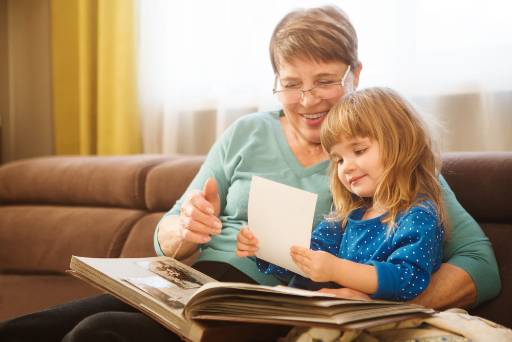 grandparent looking at a photo album with her granddaughter
