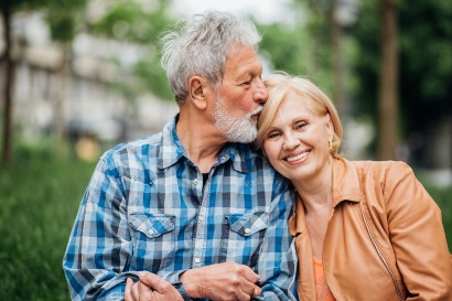senior man kissing his wife on her head as she smiles at the camera